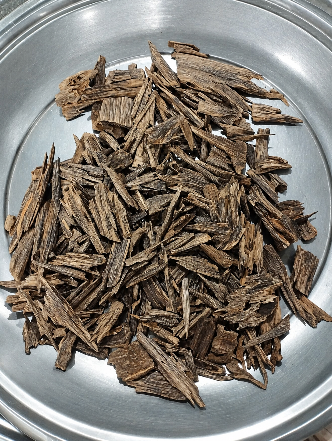 Oud Hindi Zora agarwood chips from Sujanagar, Moulvibazar, Bangladesh, shown in a steel tray
